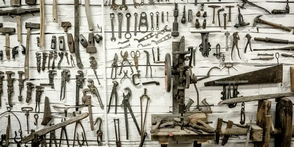 A wall covered edge to edge in old hand tools, wrenches, pliers, saws and hammers, each hung on its own nail.
